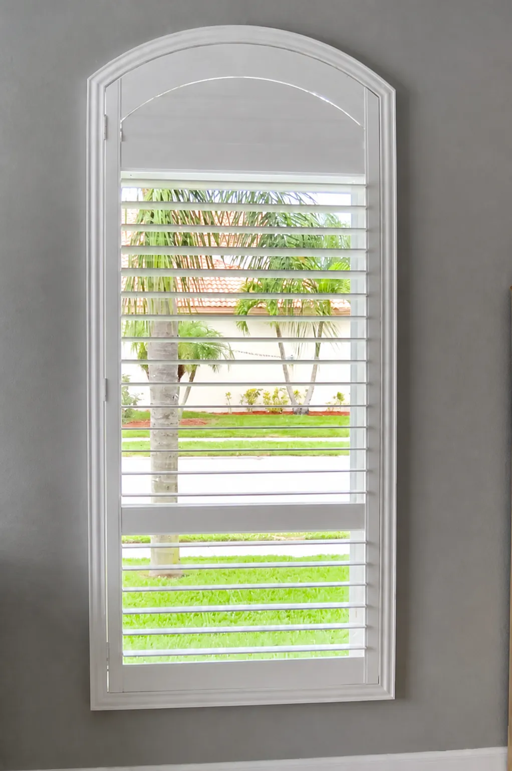 Arched plantation shutter with adjustable louvers