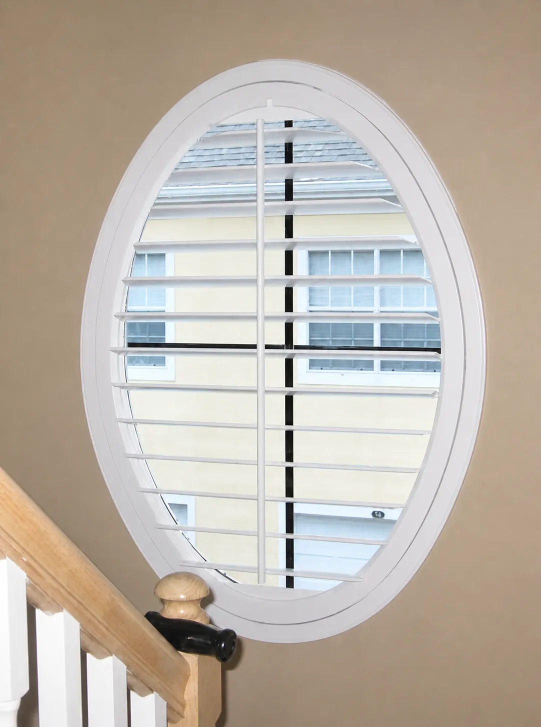 Oval custom plantation shutter beside a staircase